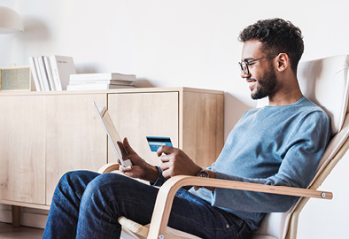 Foto de homem sentado com tablet e carto Banrisul